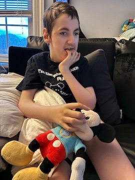 Charlie Karrat with one of his Mickey Mouse dolls and fingers in his mouth.