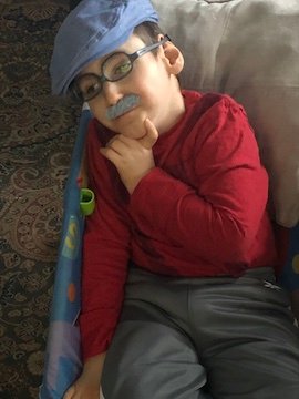 Charlie Karrat with a fake mustache and paper boy hat.